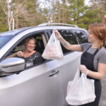 a woman hands bags of food thru a car window